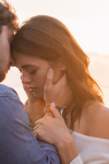 cropped image of a couple embracing on a beach near sunset.